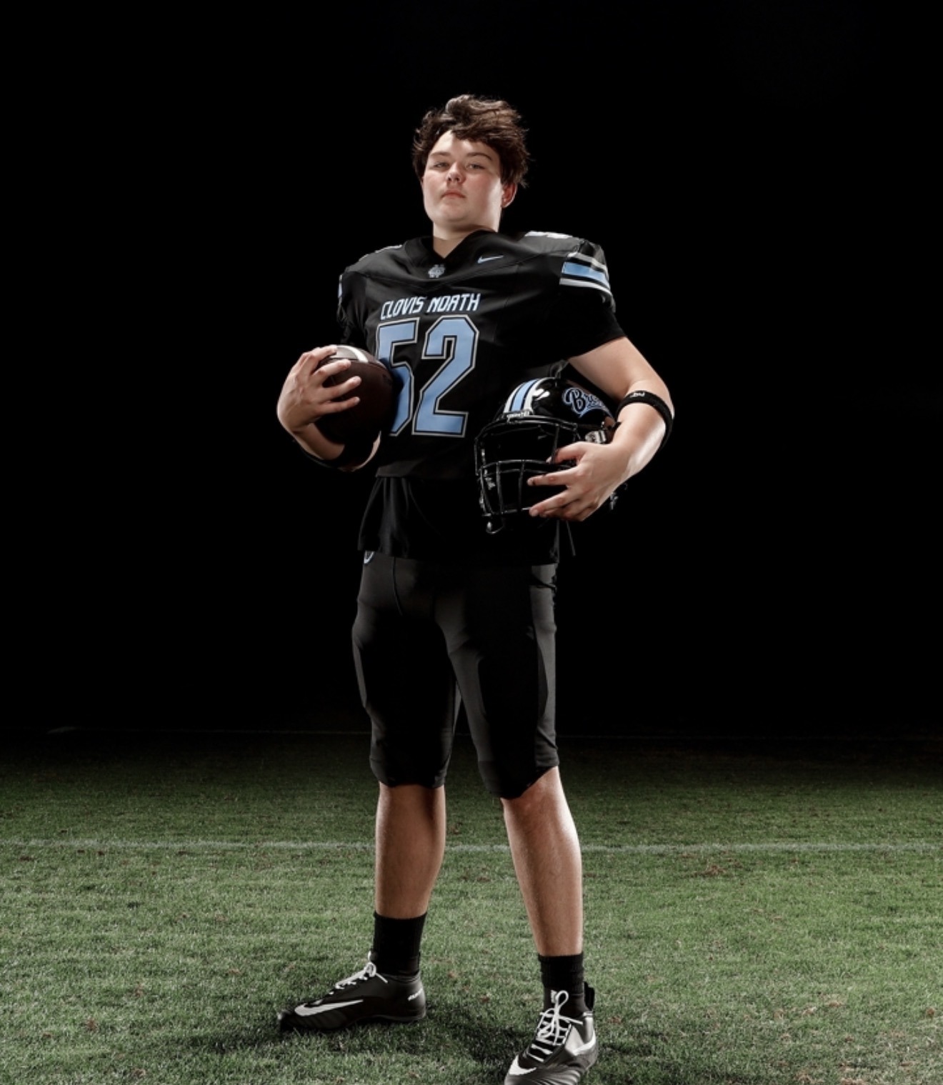 Brody in his number 52 Clovis North football uniform, holding a football and helmet